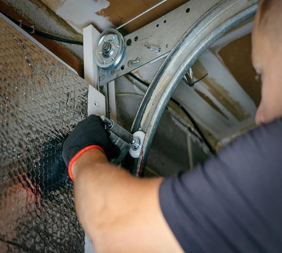 Technician wearing a black glove tightens a bolt on the rim of a circular appliance drum inside a front‑loading washing machine or dryer.